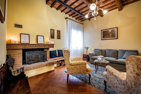 A cozy living room with a fireplace, a sofa, armchairs, and a rug.