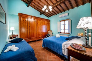 A room with two beds, a wooden wardrobe, a radiator, and a window with curtains.