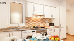 Uma cozinha moderna com armários brancos, bancada de granito e uma área de jantar posta para uma refeição.