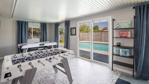 A room with a foosball table, a pool, and shelves with board games. - Coffee Lovers Paradise (Scottsdale)