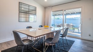 Un comedor moderno con una mesa de vidrio, cuatro sillas y un espejo decorativo en la pared.
