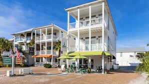 Un immeuble situé en bord de mer, doté de nombreux balcons, d’un espace de détente extérieur et d’enseignes indiquant la présence d’un café et d’un bar à jus.