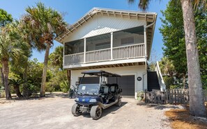 Un bâtiment à deux étages doté d’un balcon, d’une voiturette de golf et d’un garage.
