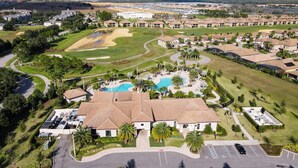 An aerial view of a golf course with a swimming pool, residential buildings, and a parking area. - 8BR Gaming Retreat, Pool & Theatre + 1 Night Free (Champions Gate)