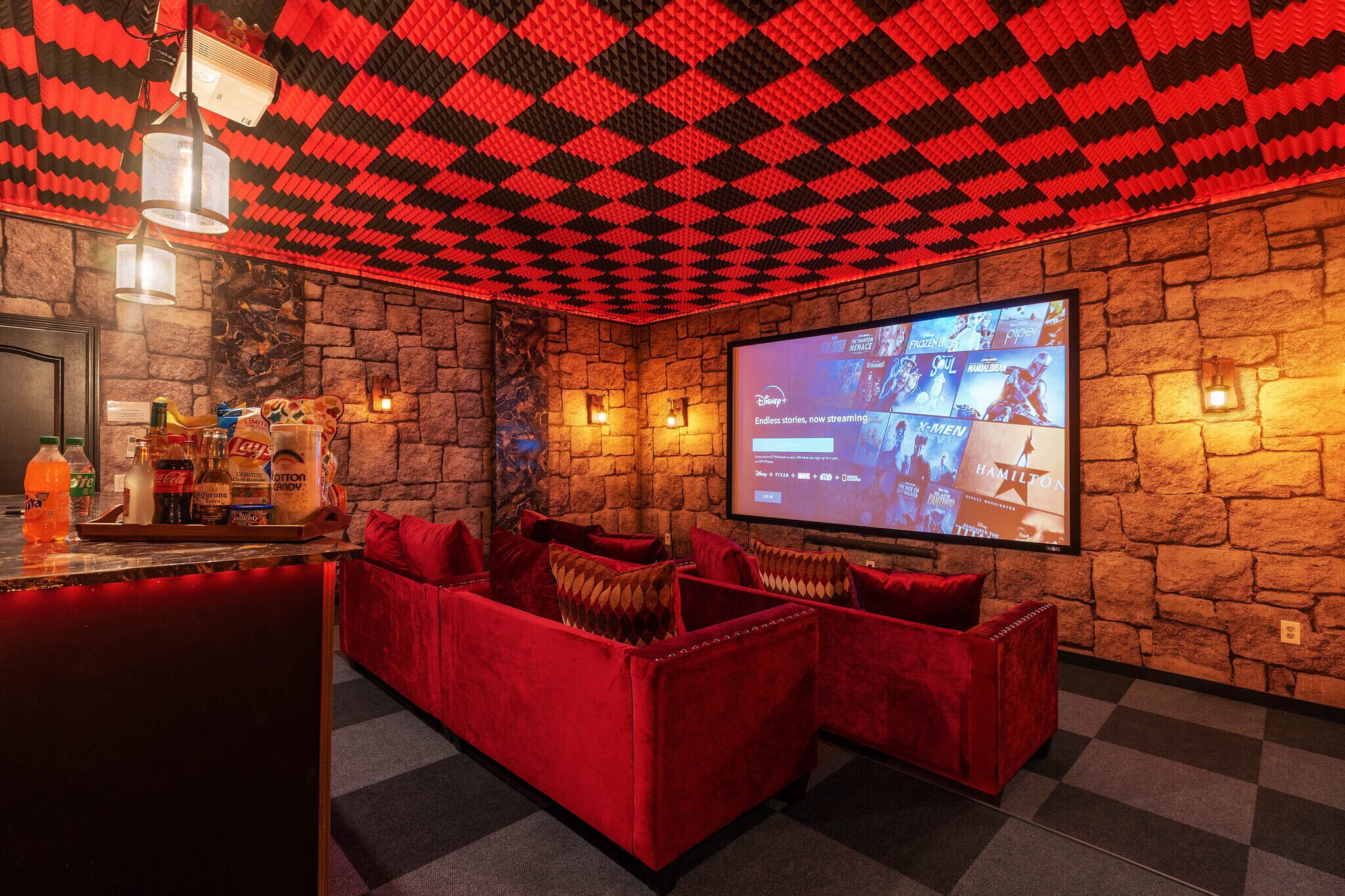 Tunnelmallinen huone, jossa on kiviseinä, punainen sohva ja litteänäyttöinen televisio, josta voi katsoa Disney+-palvelun sisältöä.