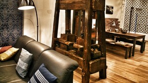 Ein Zimmer mit einem Holzschranks, einem Ledersofa mit gemusterten Kissen, einer Stehlampe und einer Ziegelwand.