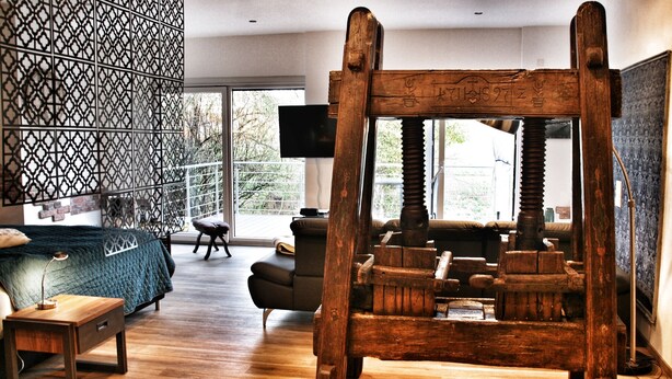 Ein modernes Wohnzimmer mit einer großen Holzschaukel, einem Sofa, einem Couchtisch und einer Wand mit Muster.