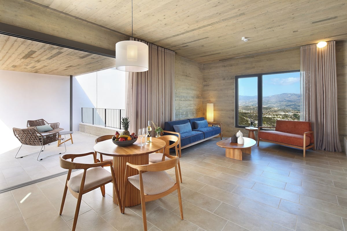 A spacious living area with a dining set, a sofa, and a view of the outdoors.