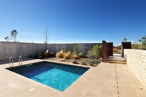 Relax by the rectangular pool surrounded by a tiled deck and lush landscaping.