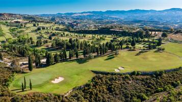 Experience the expansive golf course with well-maintained fairways, greens, and sand bunkers set amidst dense tree clusters and hilly terrain.