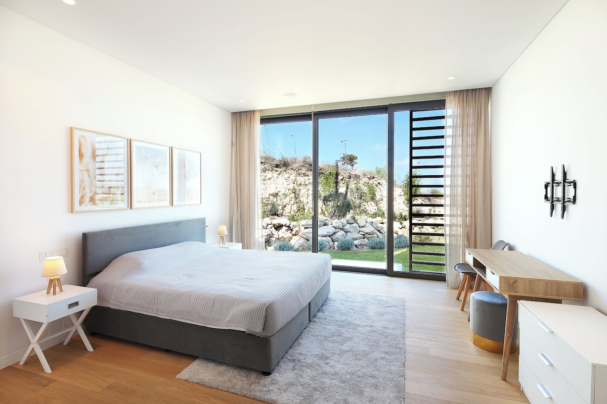 A modern bedroom with a bed, bedside table, desk, and chairs.