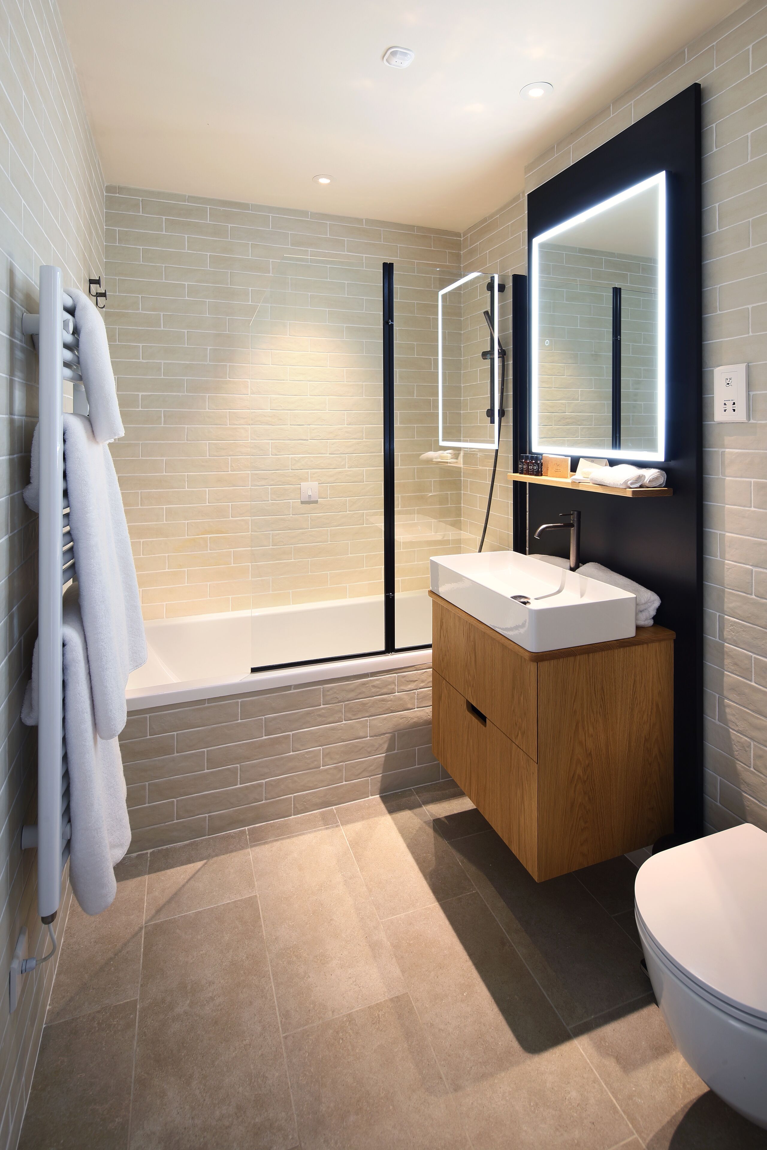 A modern bathroom with a white sink, wooden vanity, and a large mirror.