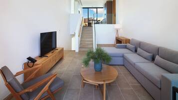 A modern living room with a sofa, a TV, a wooden coffee table, and a staircase leading to an upper floor.