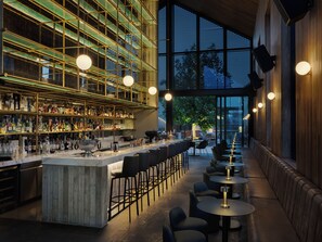 A bar with a high ceiling, a bar counter, and seating area.