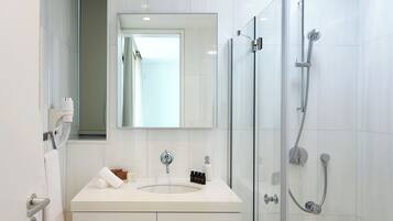 A modern bathroom with a glass-enclosed shower, a white vanity, and a large mirror.