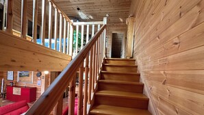 A wooden staircase with a railing leading to an upper level.