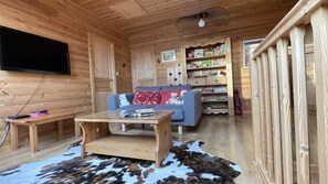 Um interior de madeira com um sofá, uma mesa de centro, uma televisão e uma estante de livros.