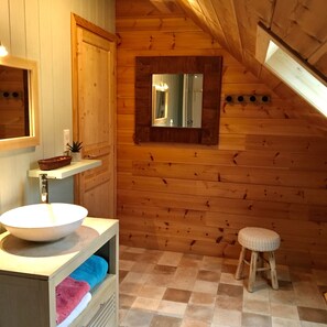 A wooden interior with a white sink, a mirror, and a stool.