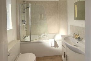 A modern bathroom with a glass-enclosed shower, a bathtub, a white sink, and a mirror.