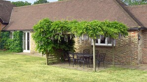 Une maison en briques avec un patio couvert, une clôture en bois et un jardin.