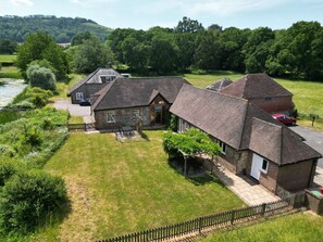 Ein Landhaus mit Garten, Teich und geparktem Auto.