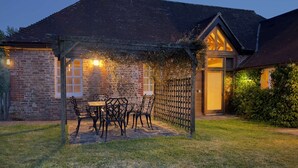 A covered outdoor seating area with a table and chairs, a stone wall, and a wooden fence. - Within the South Downs National Park, 7 miles north of Brighton. (Hassocks)