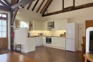 Una cocina con armarios blancos, microondas, horno y refrigerador.