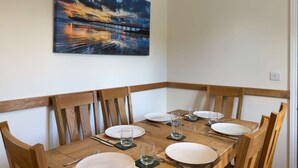 A dining area with a wooden table set for four, chairs, and a painting of a sunset over a bridge on the wall. - Within the South Downs National Park, 7 miles north of Brighton. (Hassocks)
