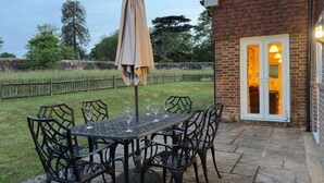 An outdoor patio with a table and chairs, a covered umbrella, and a brick building with a door. - Within the South Downs National Park, 7 miles north of Brighton. (Hassocks)