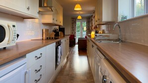 A narrow kitchen with a microwave, stove, and sink. - Within the South Downs National Park, 7 miles north of Brighton. (Hassocks)