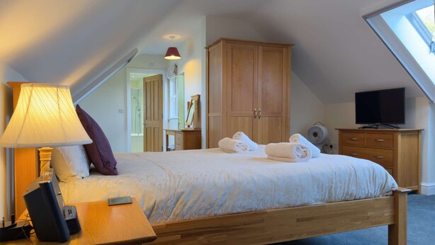 A bedroom with a bed, a desk with a lamp, a television, and a wardrobe. - Within the South Downs National Park, 7 miles north of Brighton. (Hassocks)