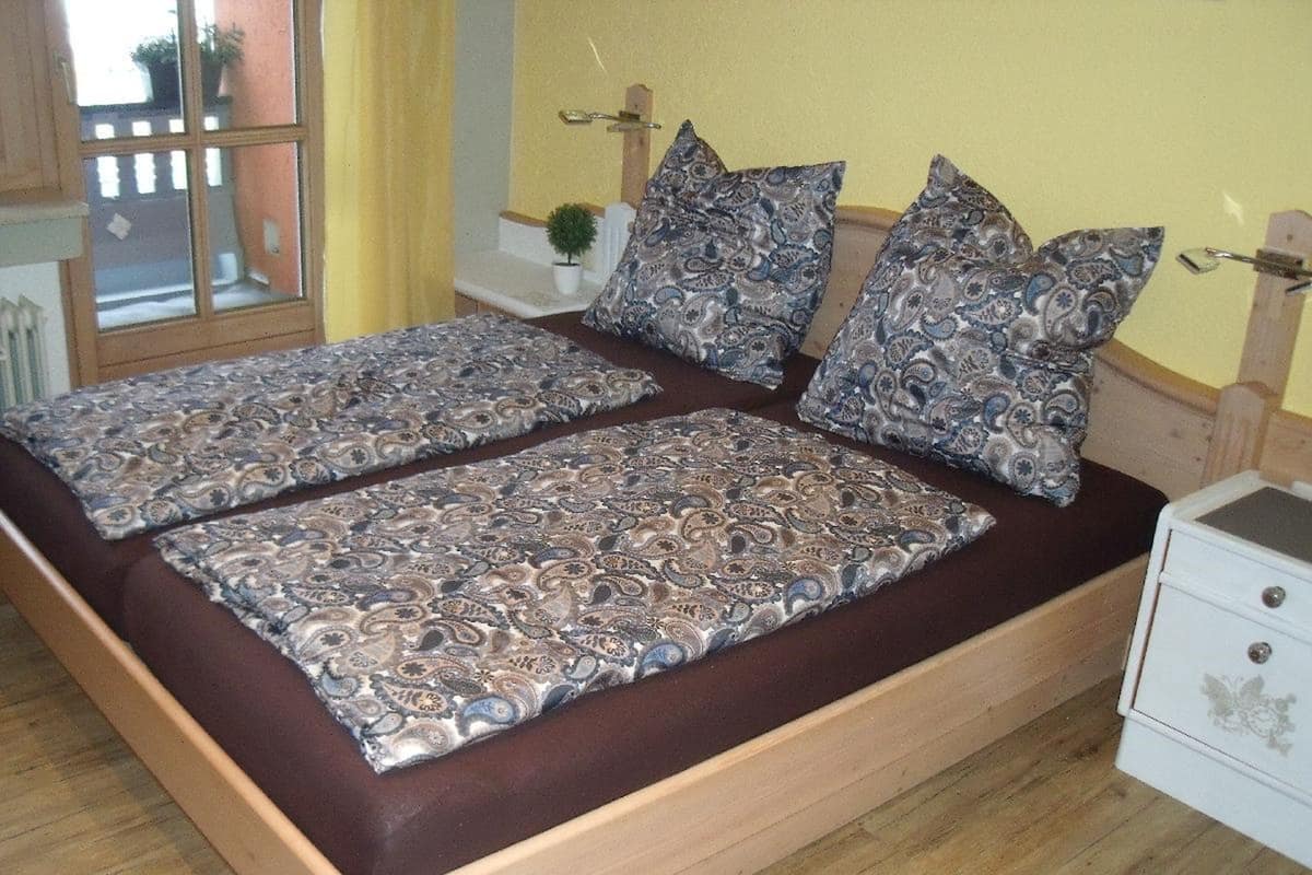 Un lit double avec une literie à motifs, une table de chevet et une fenêtre avec des rideaux.