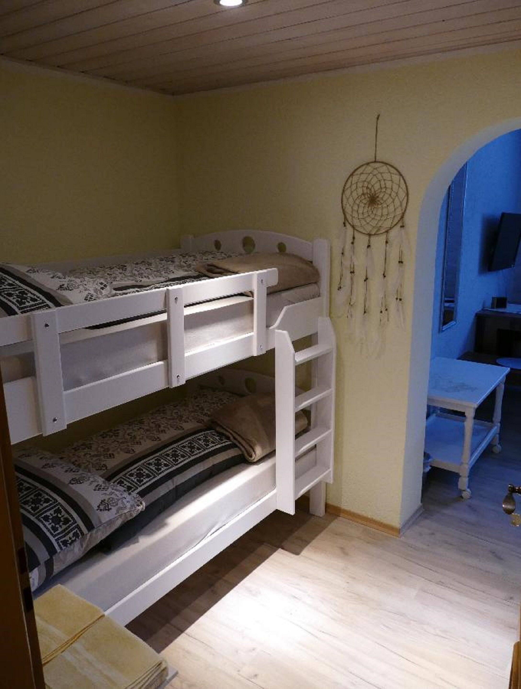 A bunk bed room with a dreamcatcher on the wall and a TV in the corner.