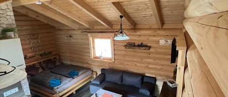 A cabin interior with a kitchenette, a sofa, a dining table, and a small window.