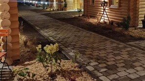 Une cabane en bois dotée d’un porche couvert et d’un chemin pavé menant à l’entrée.