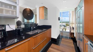Una cocina moderna con encimera negra, armarios de madera y un amplio ventanal con vistas a la ciudad.