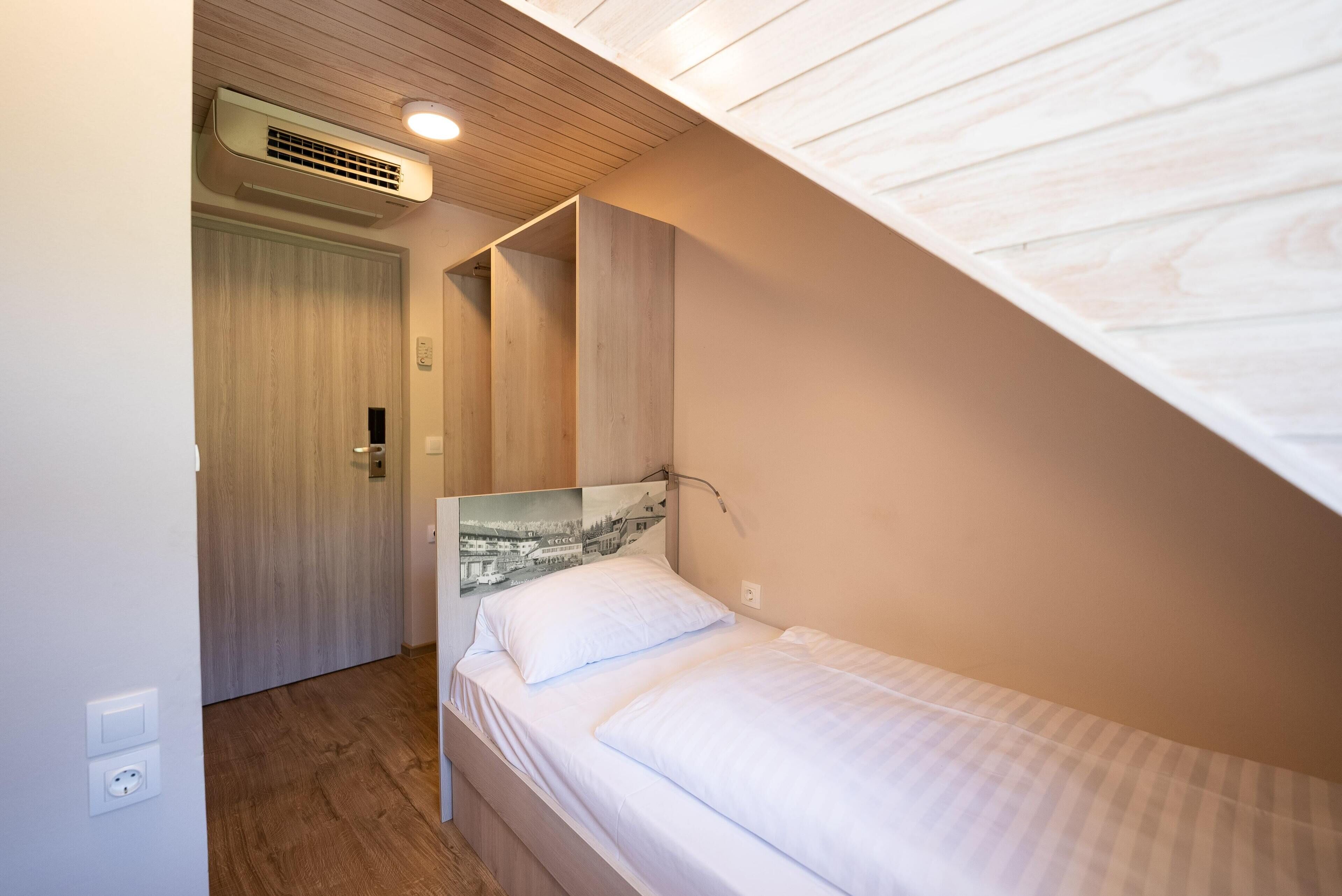 A bedroom with a bunk bed, wooden ceiling, and a wall-mounted air conditioner.