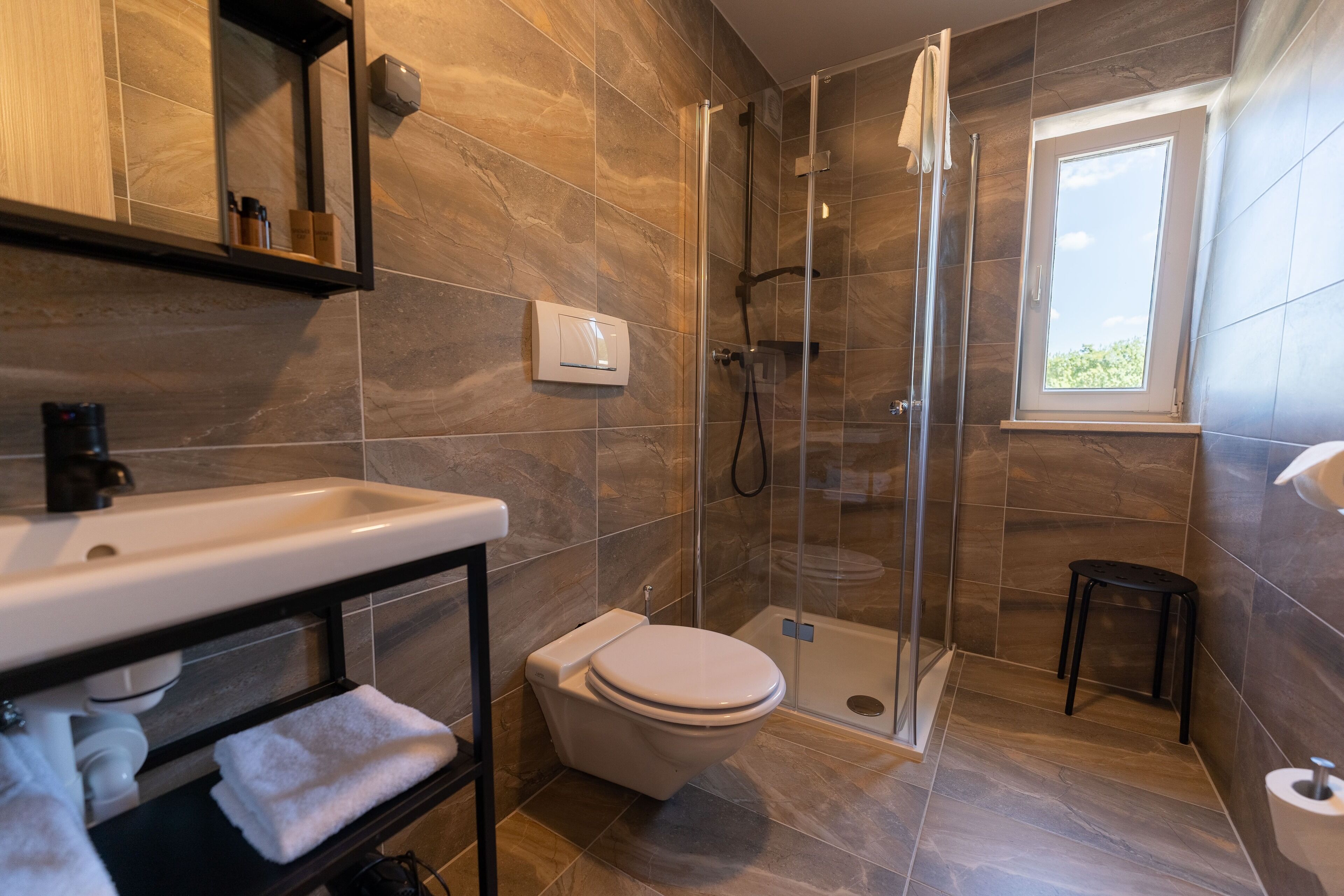 A modern bathroom with a shower, toilet, and sink.