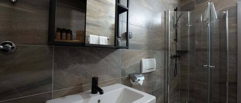 A modern bathroom with a white sink, a mirror, a glass shower enclosure, and a toilet.
