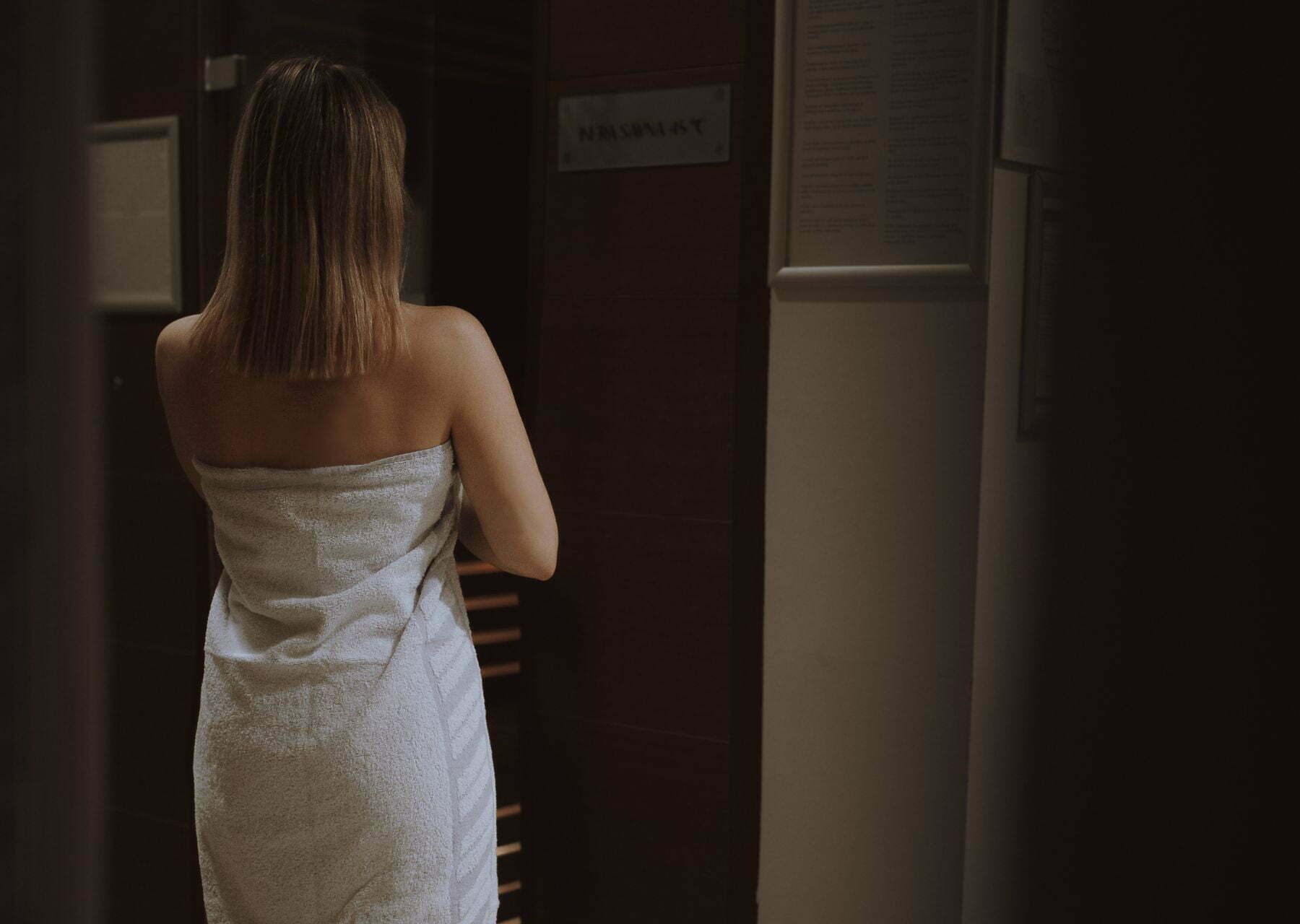 A person in a towel walking down a hallway with a sign that reads "NIGHT STAY".