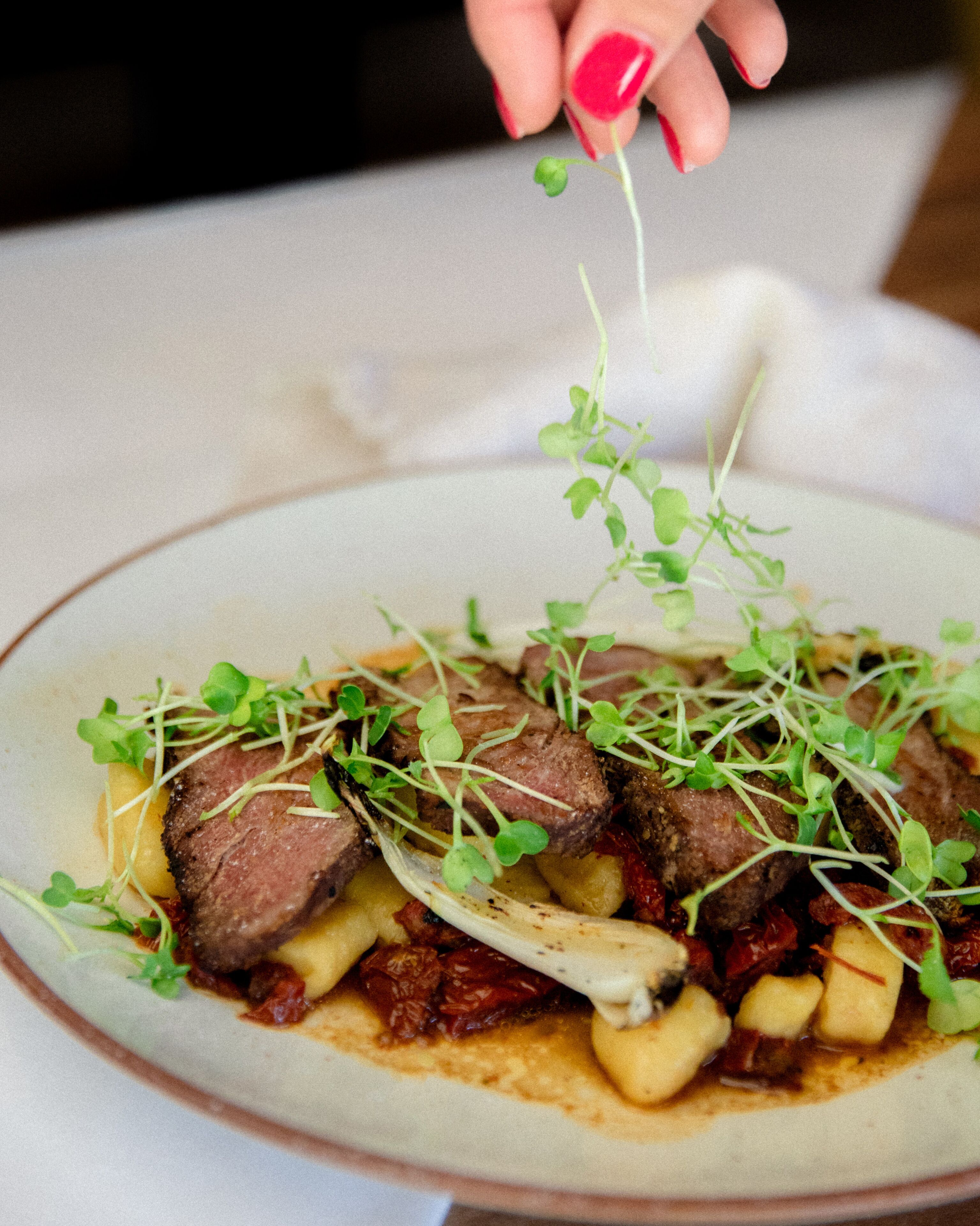 Un plato de comida con carne, patatas y vegetales verdes.