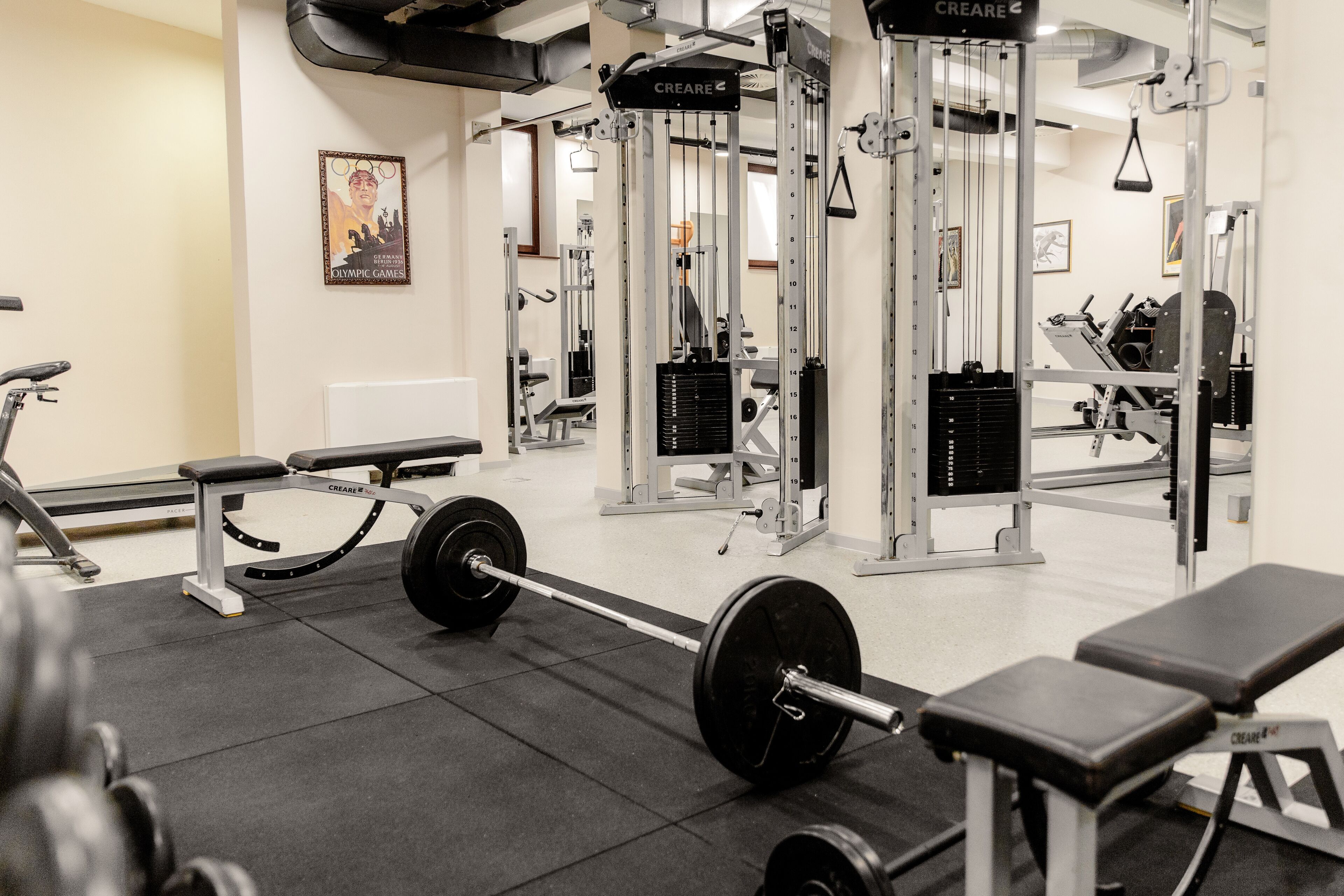 A gym with weightlifting equipment, benches, and a mirror.