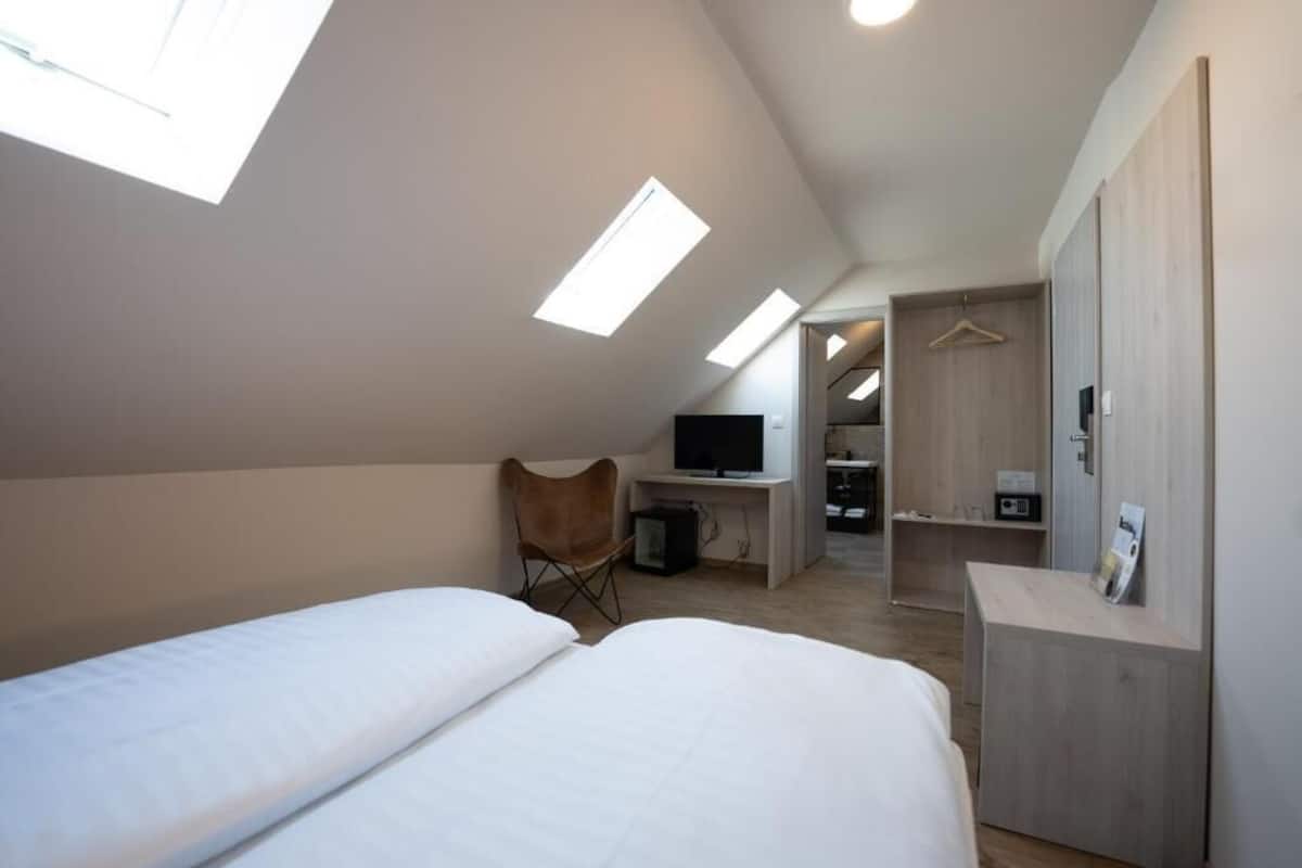 A bedroom with two beds, a desk, a chair, and a TV.