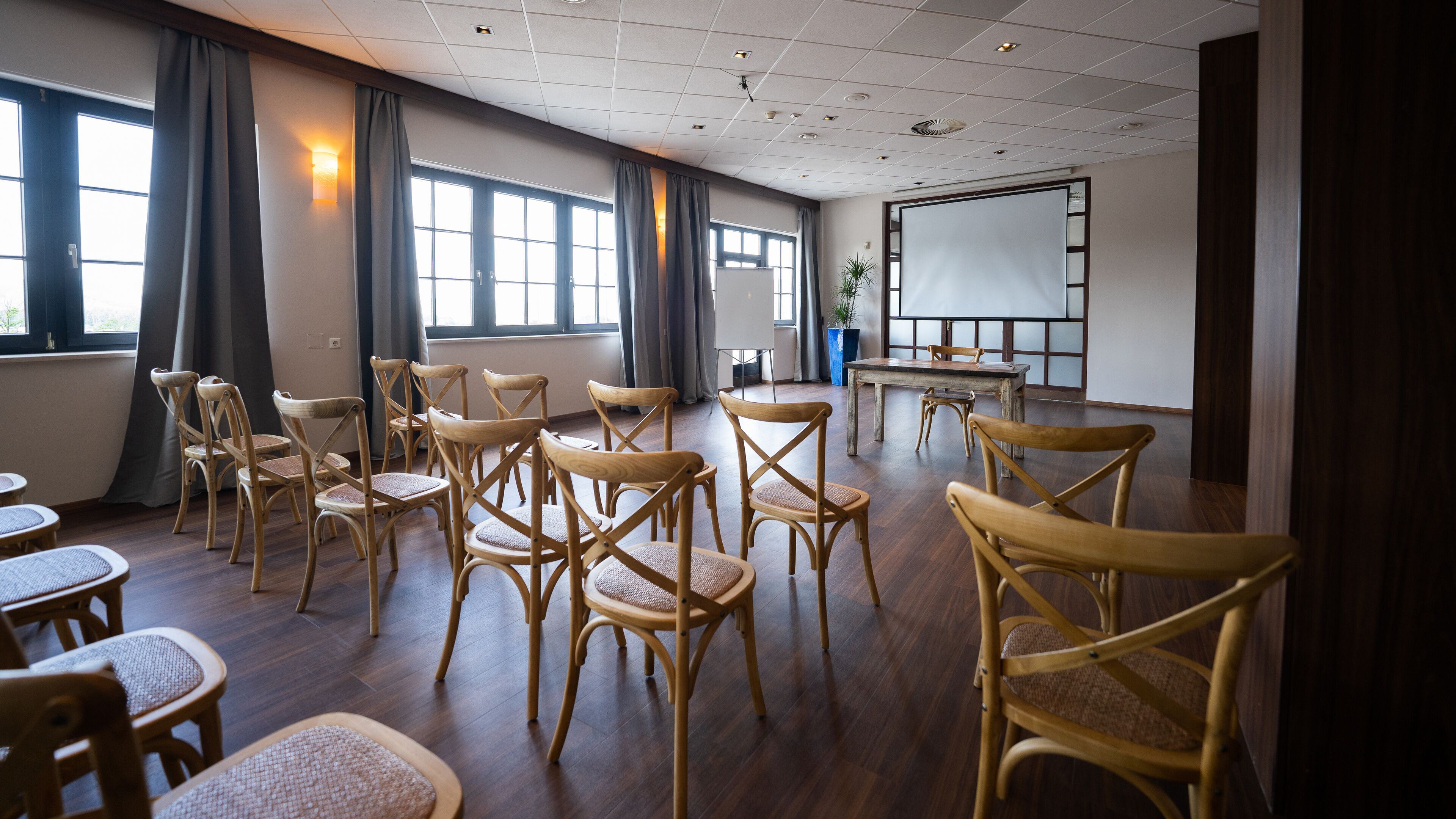A conference room with wooden chairs, a whiteboard, and a projector screen.