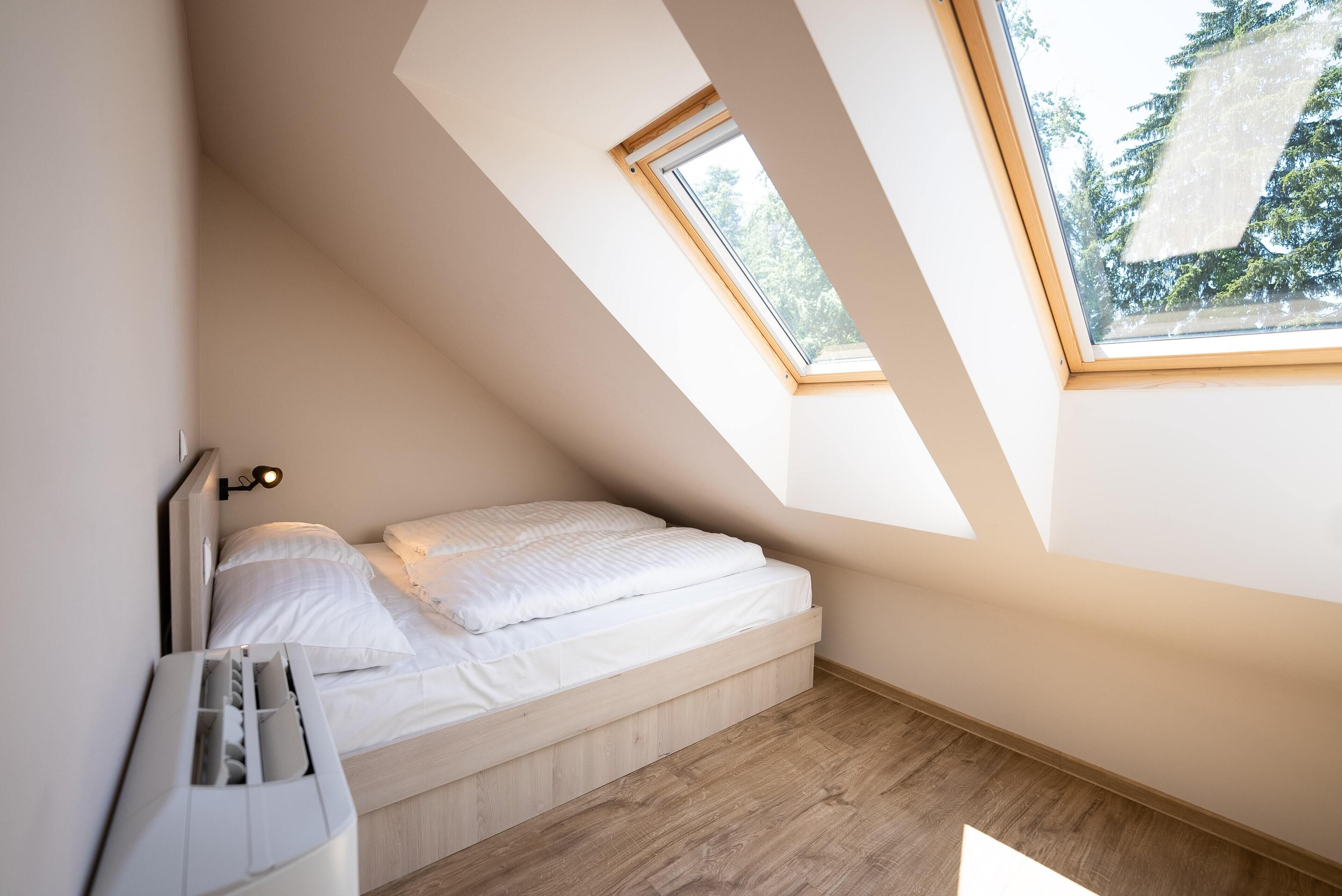 Ein kleines, modernes Schlafzimmer mit Oberlicht, einem Bett und einer fest installierten Heizung.