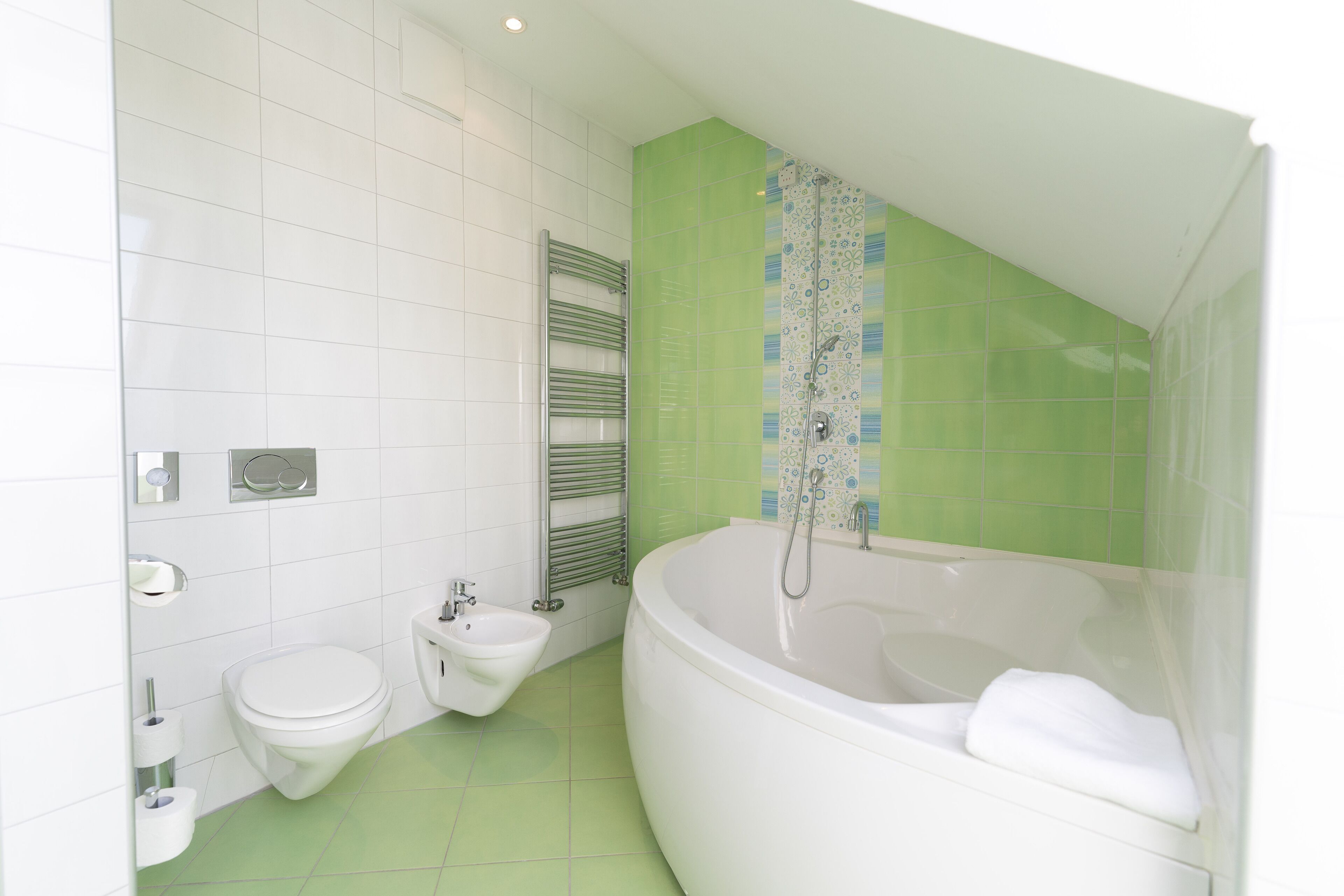 A bathroom with a white toilet, bidet, and a large bathtub.