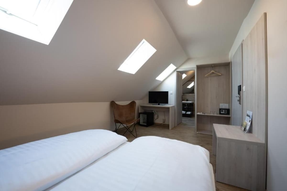 A bedroom with two beds, a desk, a chair, and a TV.