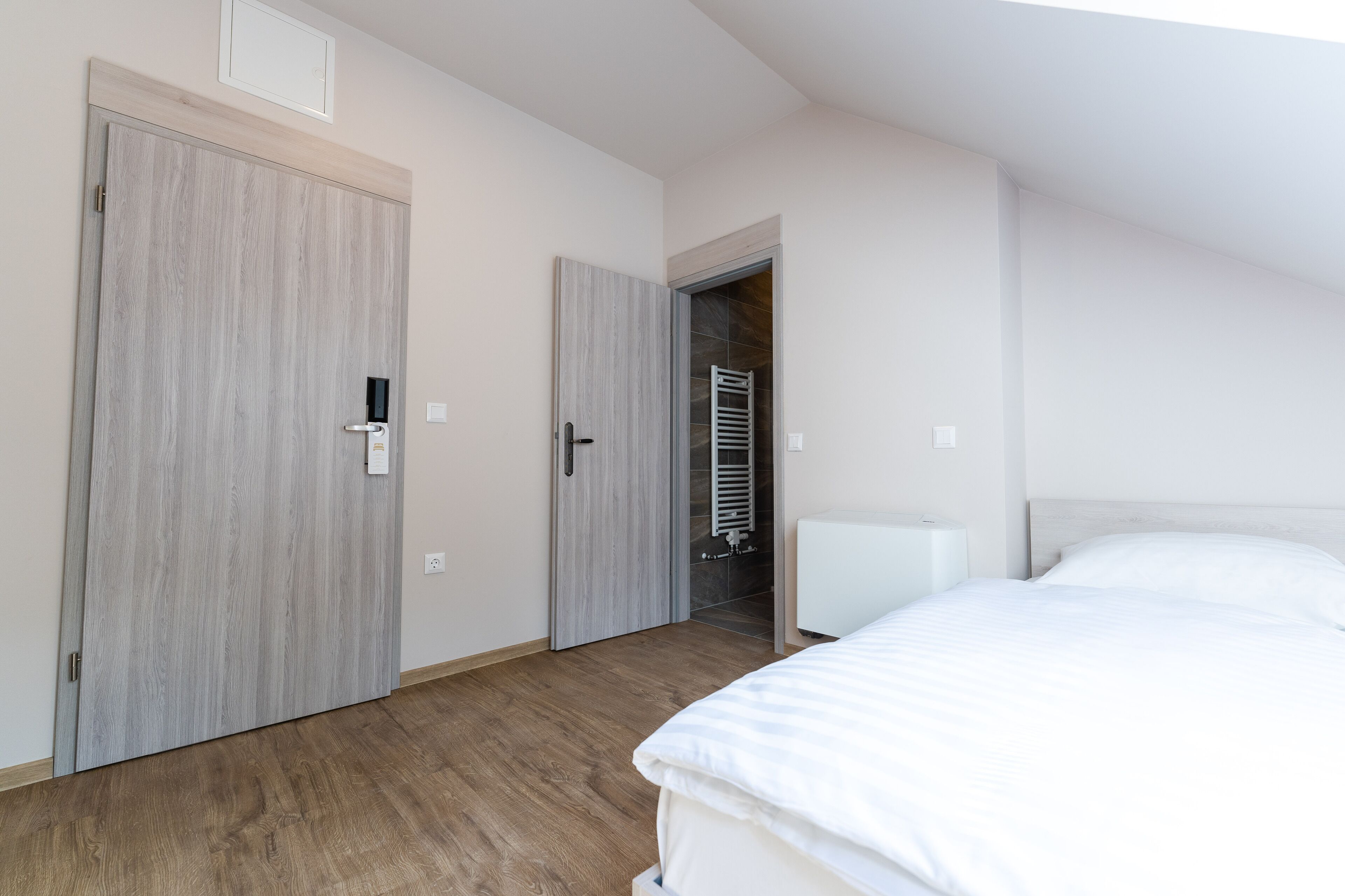 A bedroom with a bed, wooden flooring, and a wardrobe.