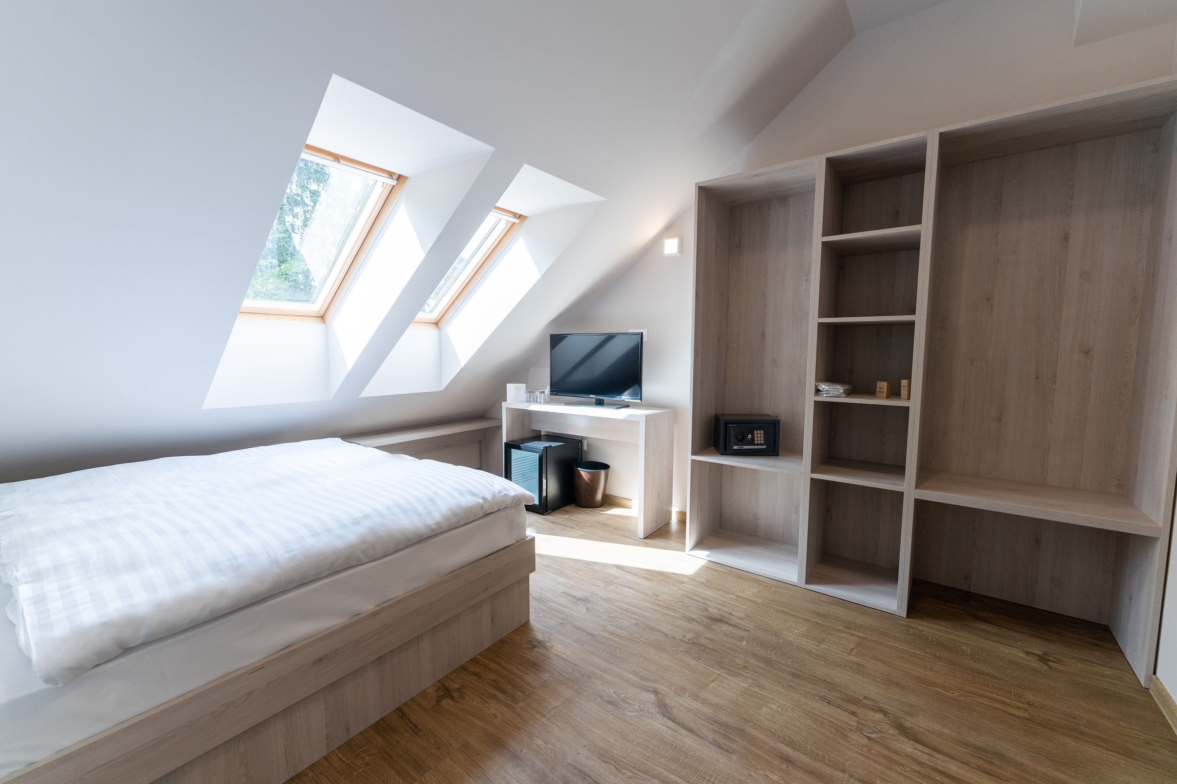 Une chambre moderne avec un lit en mezzanine, des fenêtres de toit, une télévision et des étagères intégrées.
