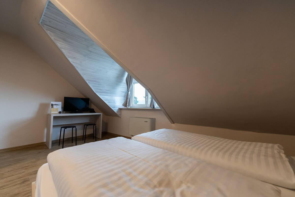 A bedroom with two beds, a desk, and a window.